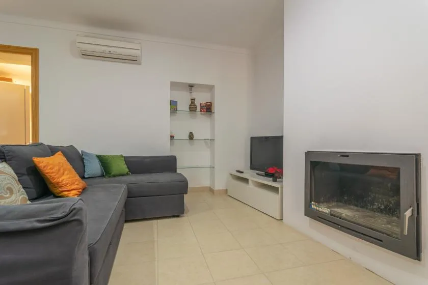 A living room with sectional seating, a television, and a built-in fireplace.