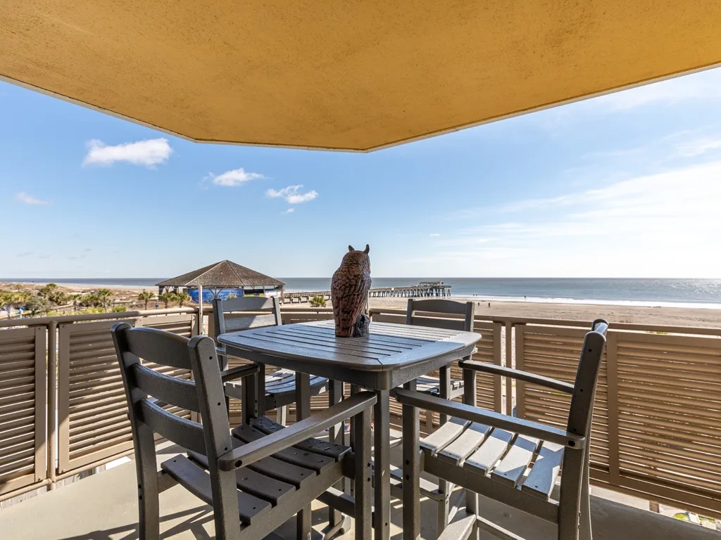 An outdoor dining area with a table and seating overlooks the ocean.