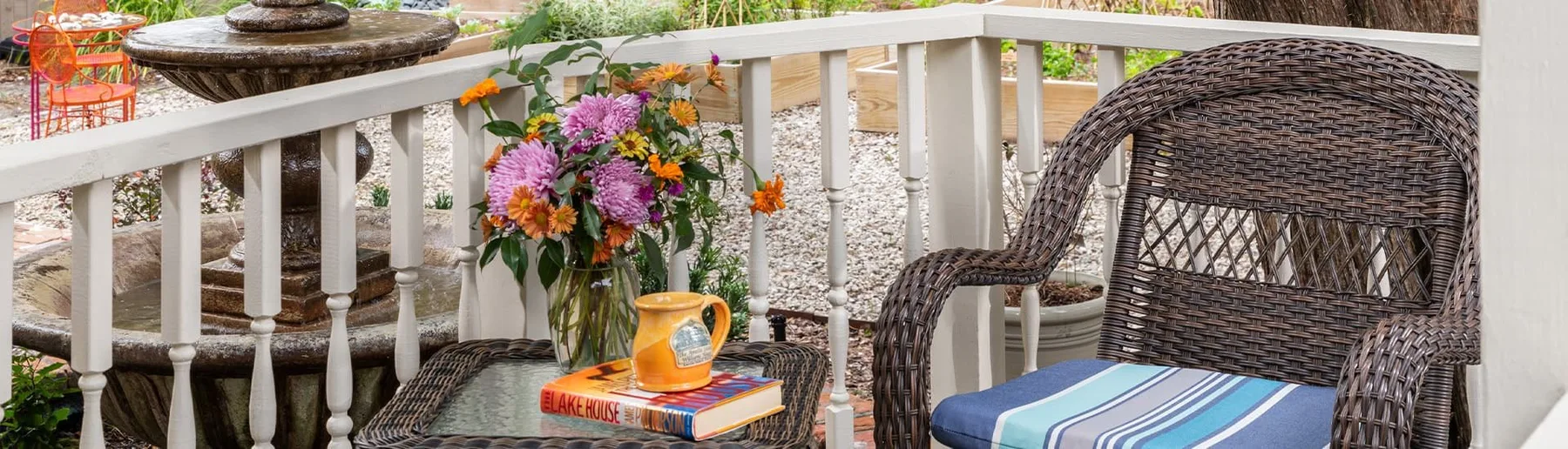 Flowers, mug, and book on a wicker patio table beside a patio chair