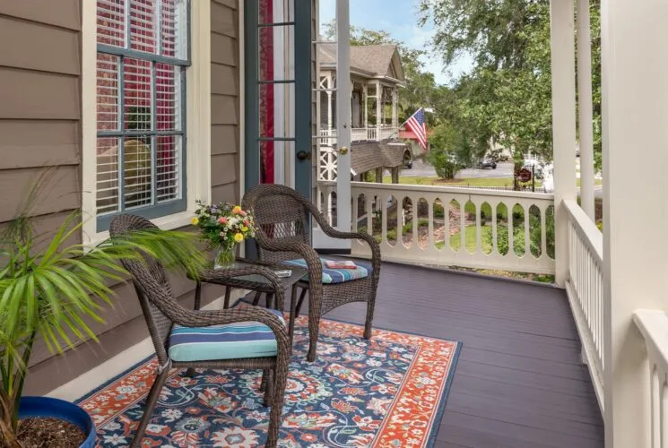 Balcony with wicker patio chairs and table, area rug, and potted plant