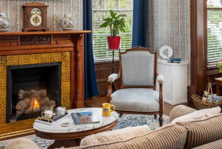 Bedroom with ornate wallpaper, hardwood flooring, sitting area, and fireplace