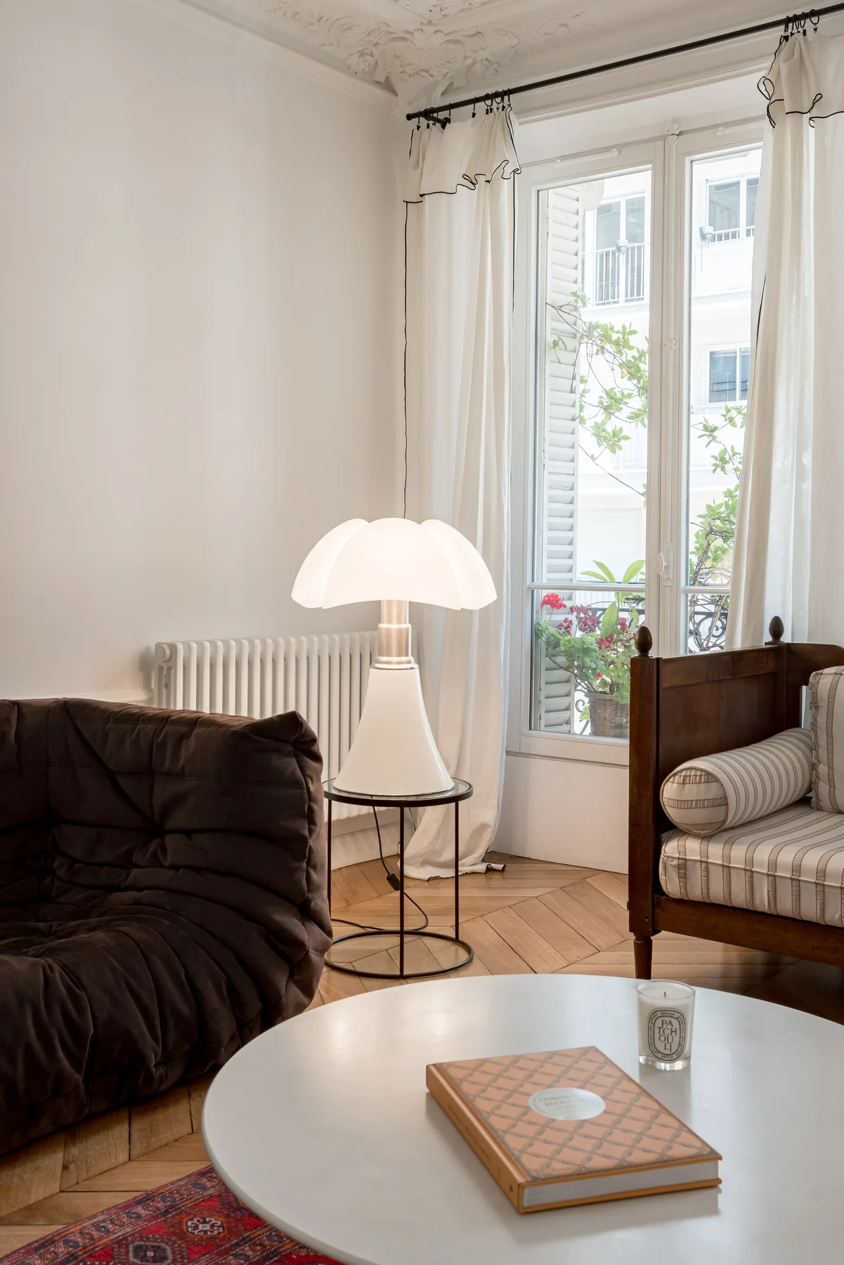 A bright sitting room with a round coffee table and tall windows.