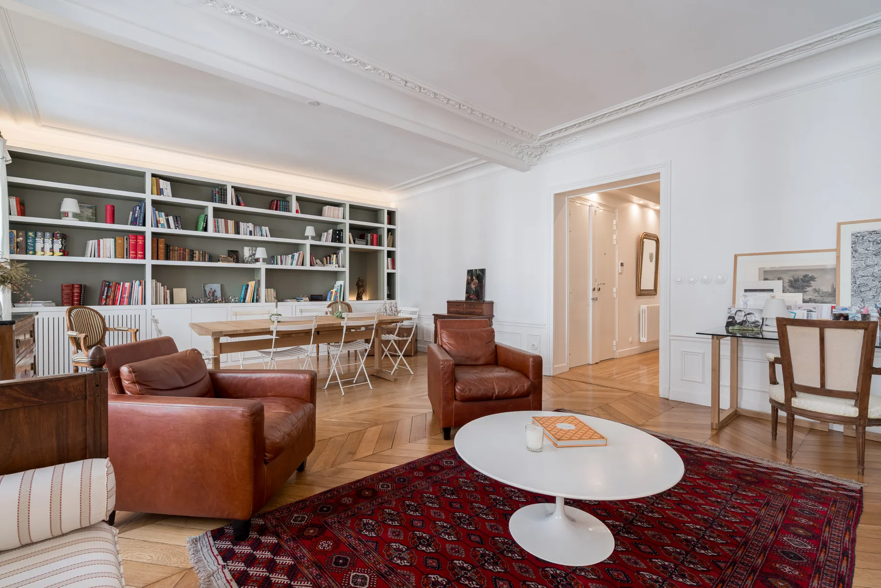 A bright living room with bookshelves, seating, and a patterned rug.