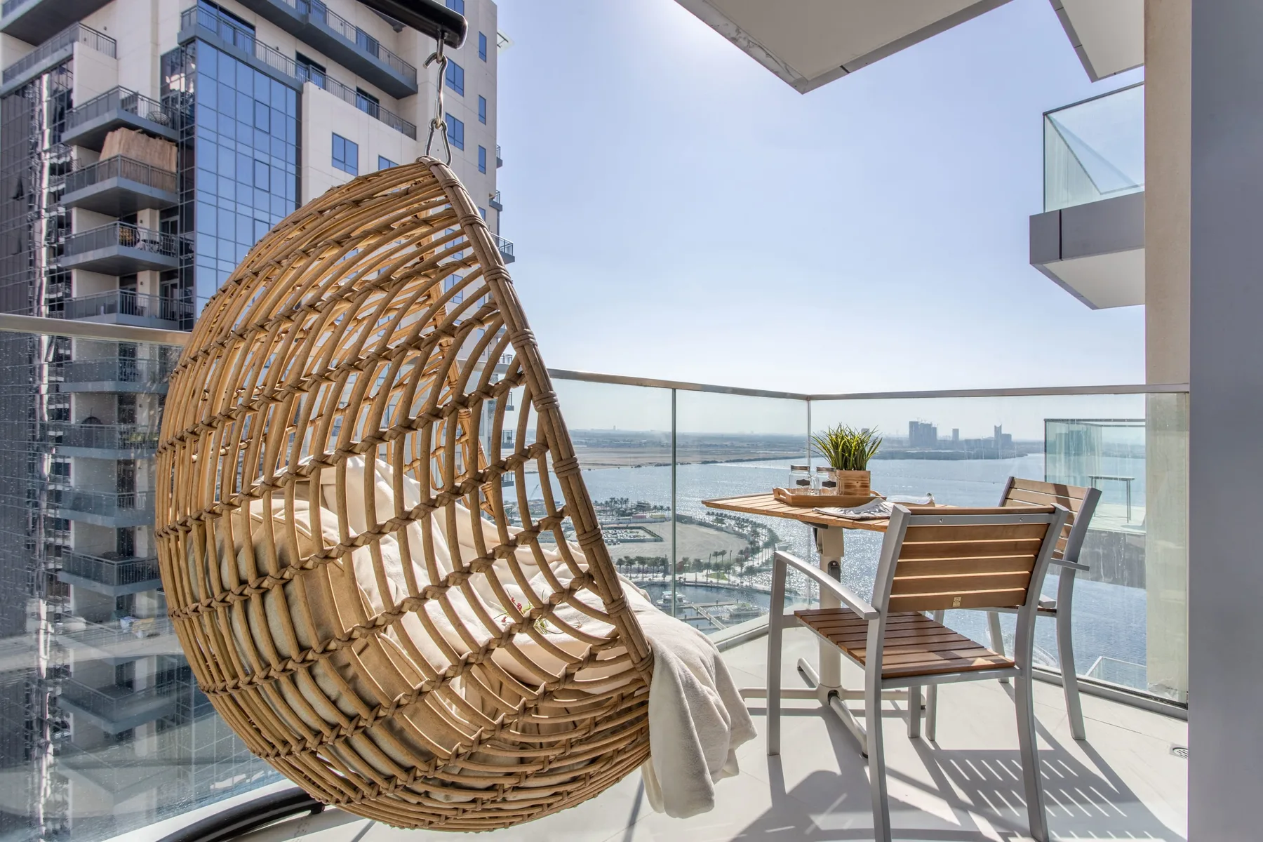 A balcony seating area overlooks the water and nearby city buildings.