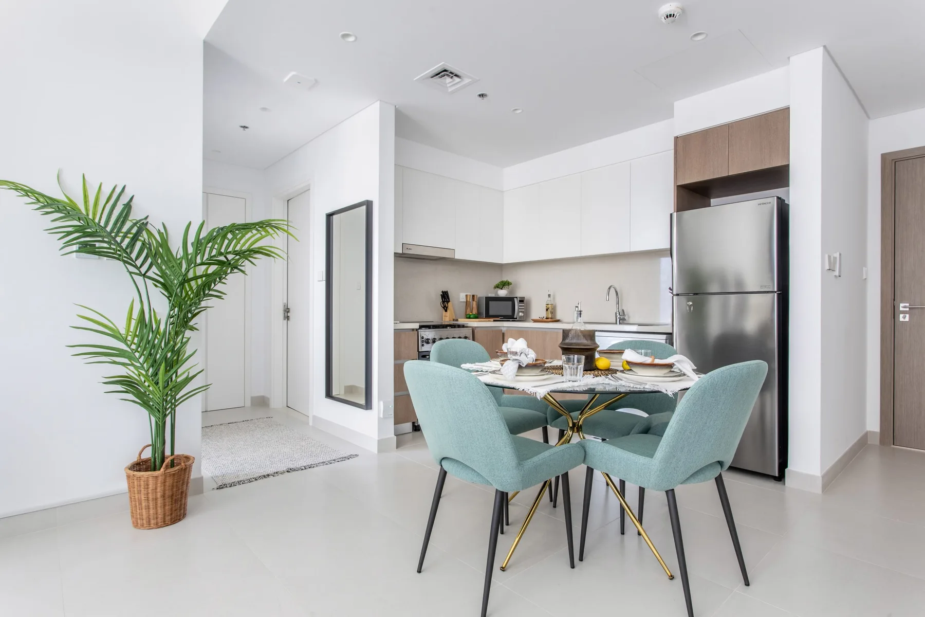 A bright kitchen and dining area with turquoise seating around a table.