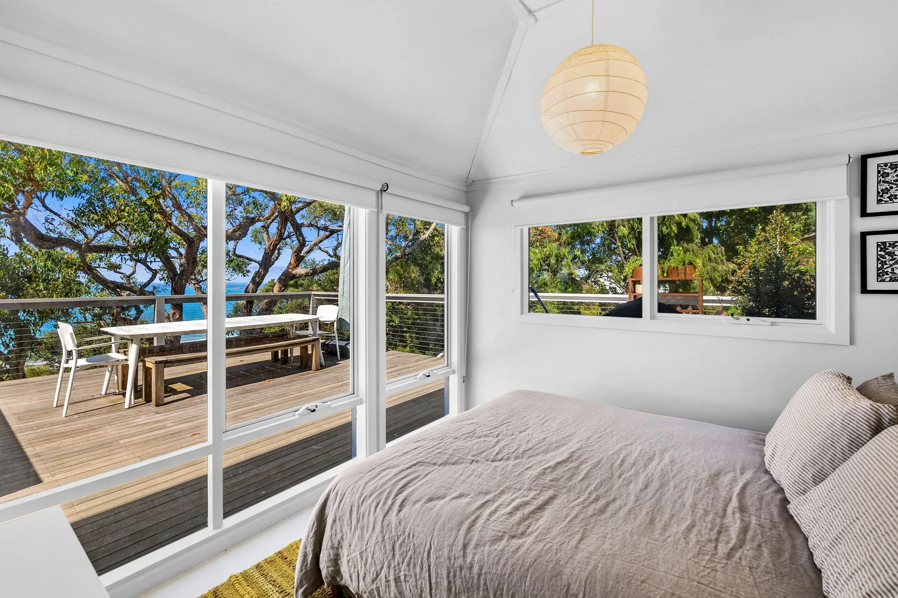 Un dormitorio luminoso con una cama junto a grandes ventanas que dan a una terraza.