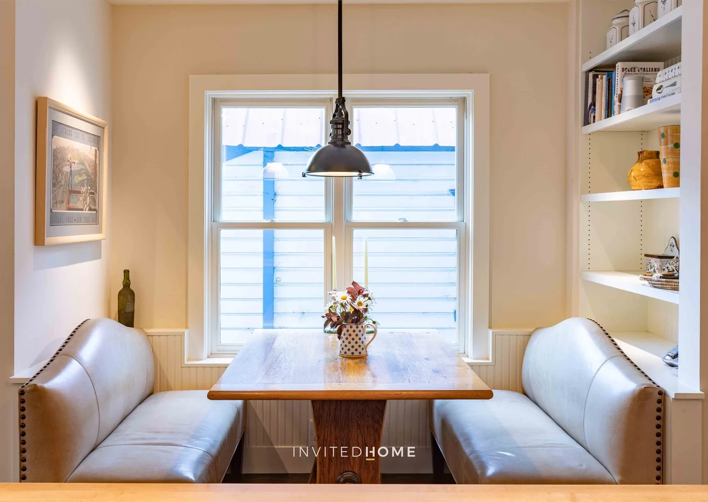 Un rincón de desayuno con asientos acolchados alrededor de una mesa de madera junto a una ventana.