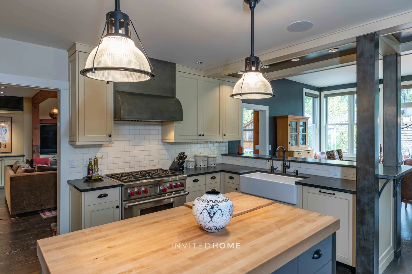 Una cocina luminosa con una gran isla de madera, gabinetes claros y lámparas colgantes.