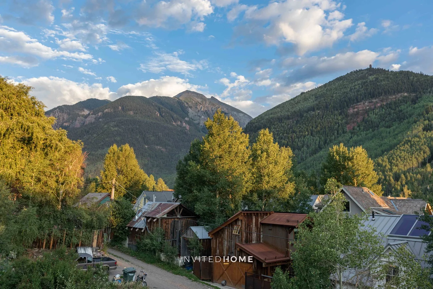 Un paisaje montañoso se alza detrás de un conjunto de casas y árboles.