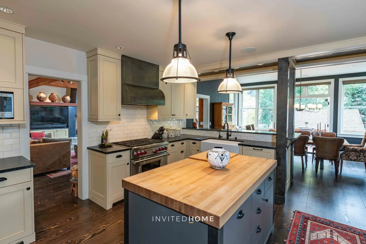 Una cocina luminosa con una isla central y comedor junto a grandes ventanales.