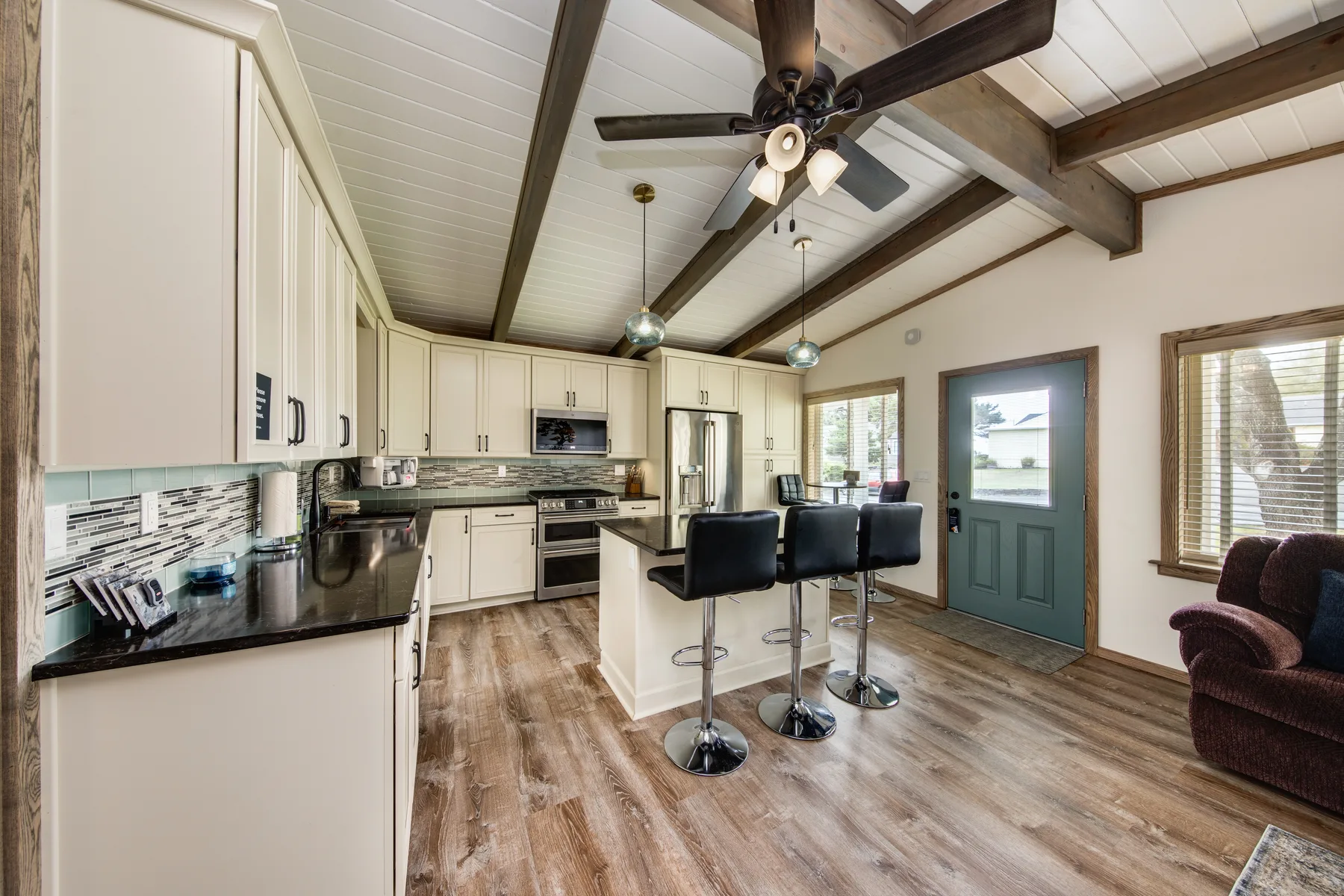 A bright kitchen with an island, bar seating, and a green exterior door.