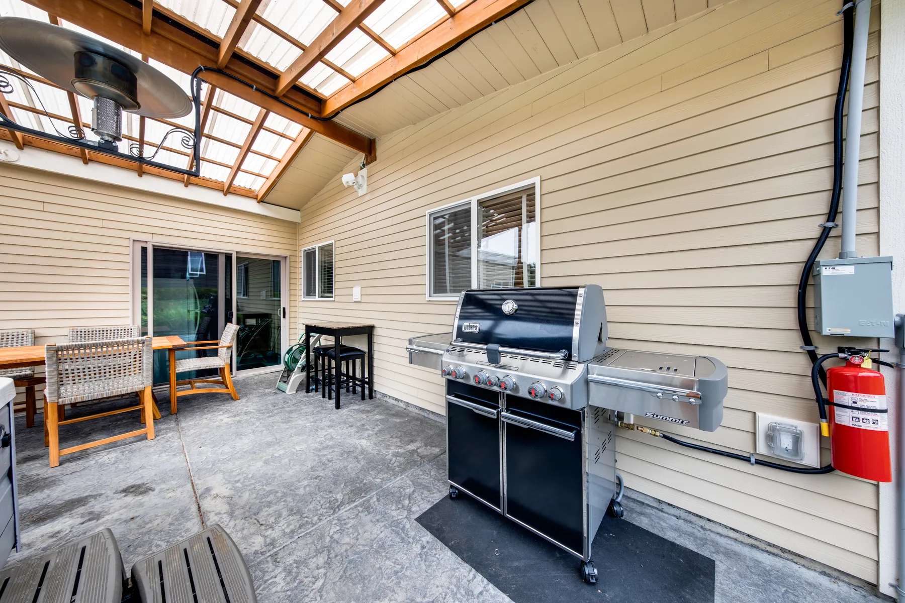 A covered patio with a large grill and outdoor seating.