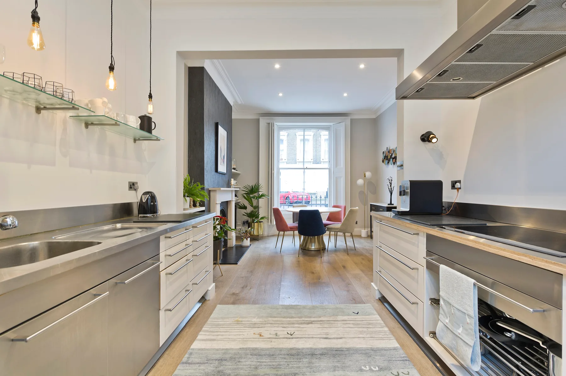 A modern kitchen opens into a dining area, with a table by the window.