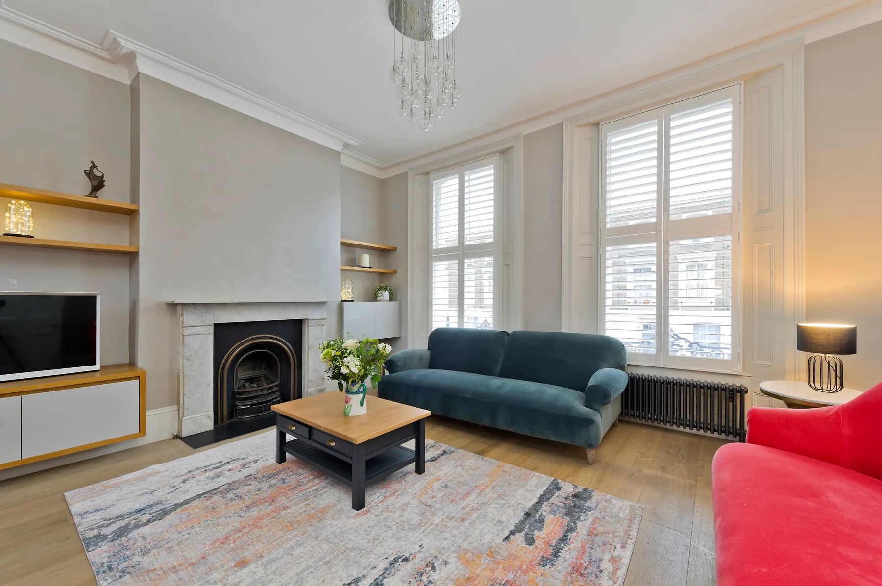 A living room with seating, a coffee table, and tall windows.