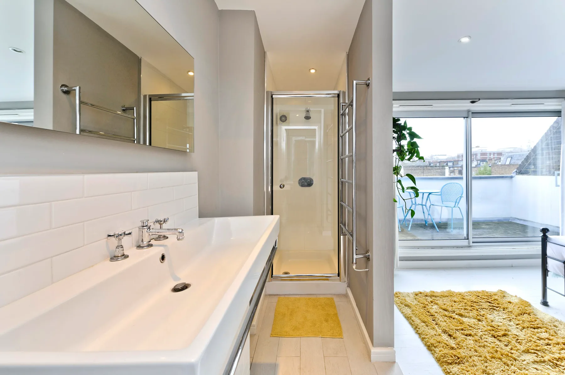 A bright bathroom with a long sink counter and a glass shower.