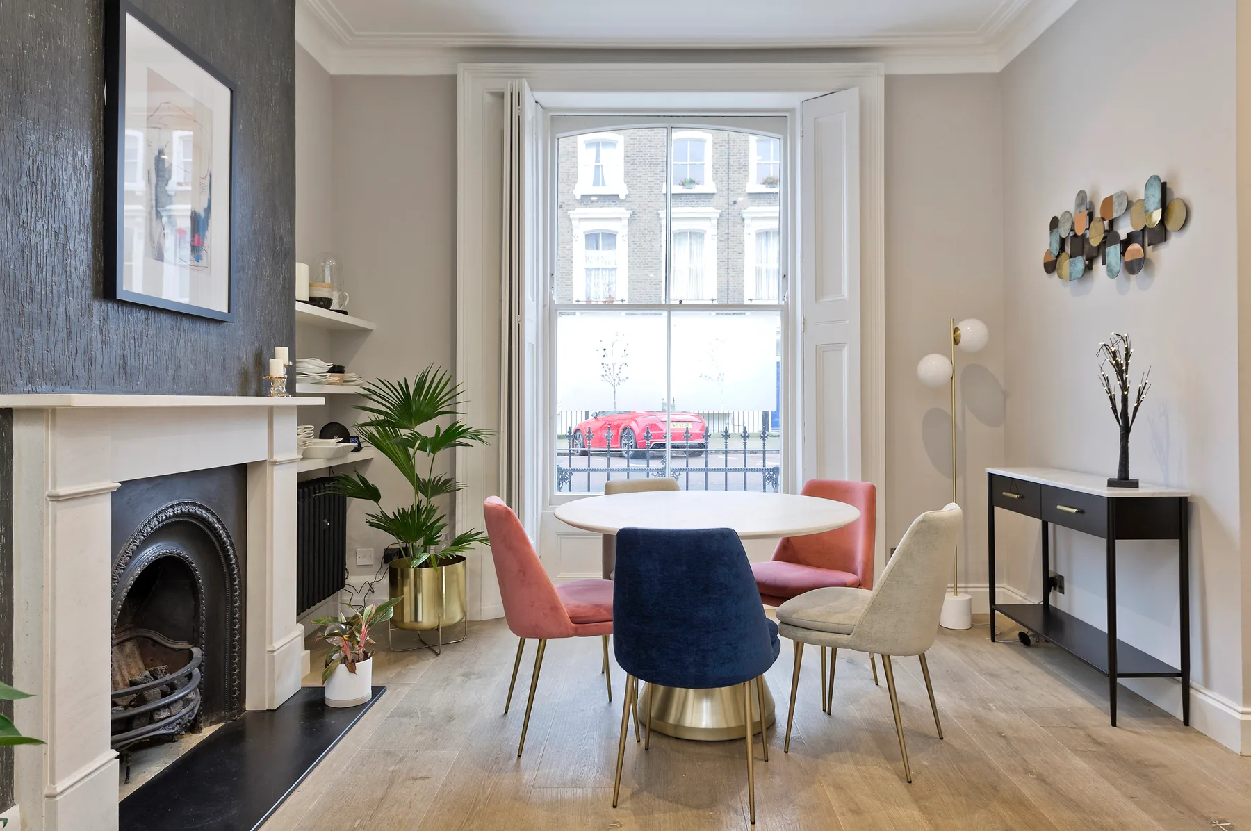 A bright living and dining room with colorful seating around a round table.