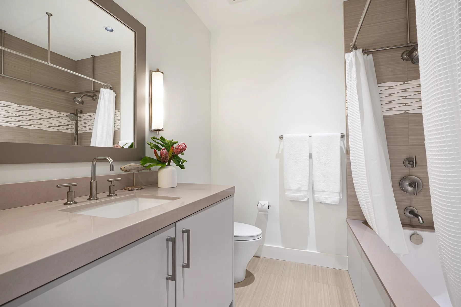 A bathroom with a vanity, mirror, toilet, and shower-tub.