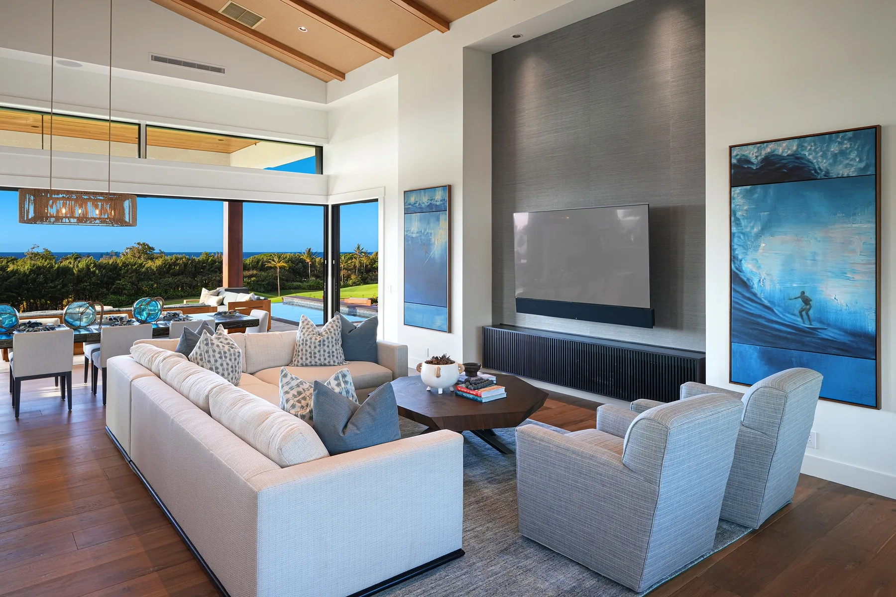 A bright living room with seating arranged around a low table and a wall-mounted television.