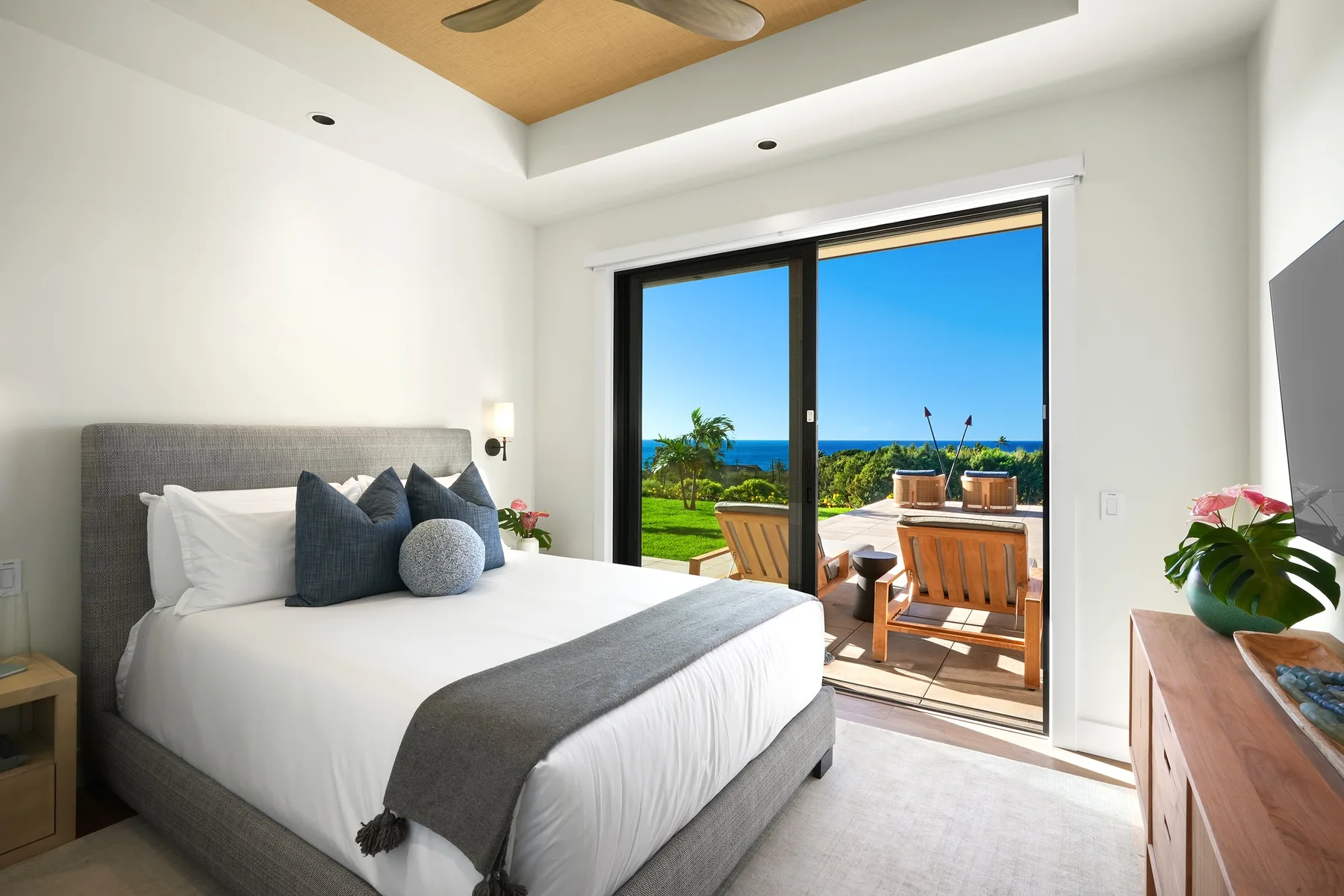 A bedroom with a neatly made bed beside glass doors opening onto a patio.