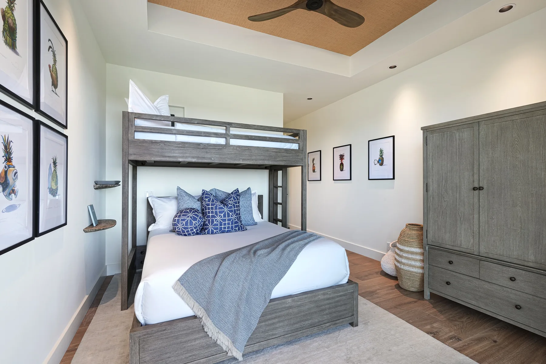 A bedroom with a raised wooden bed frame, blue pillows, and a large gray wardrobe.