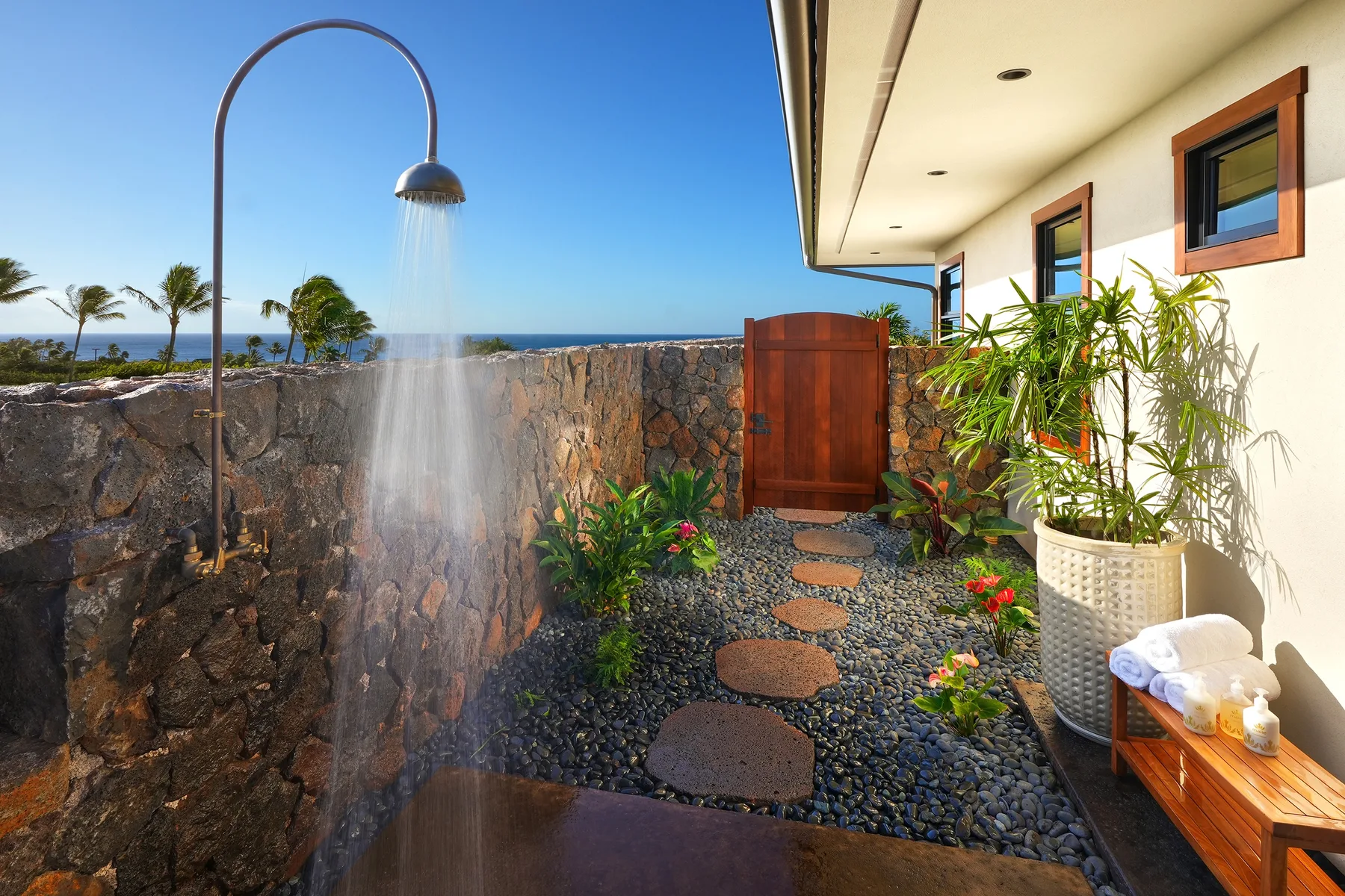 An outdoor shower area with a stone path beside a building.