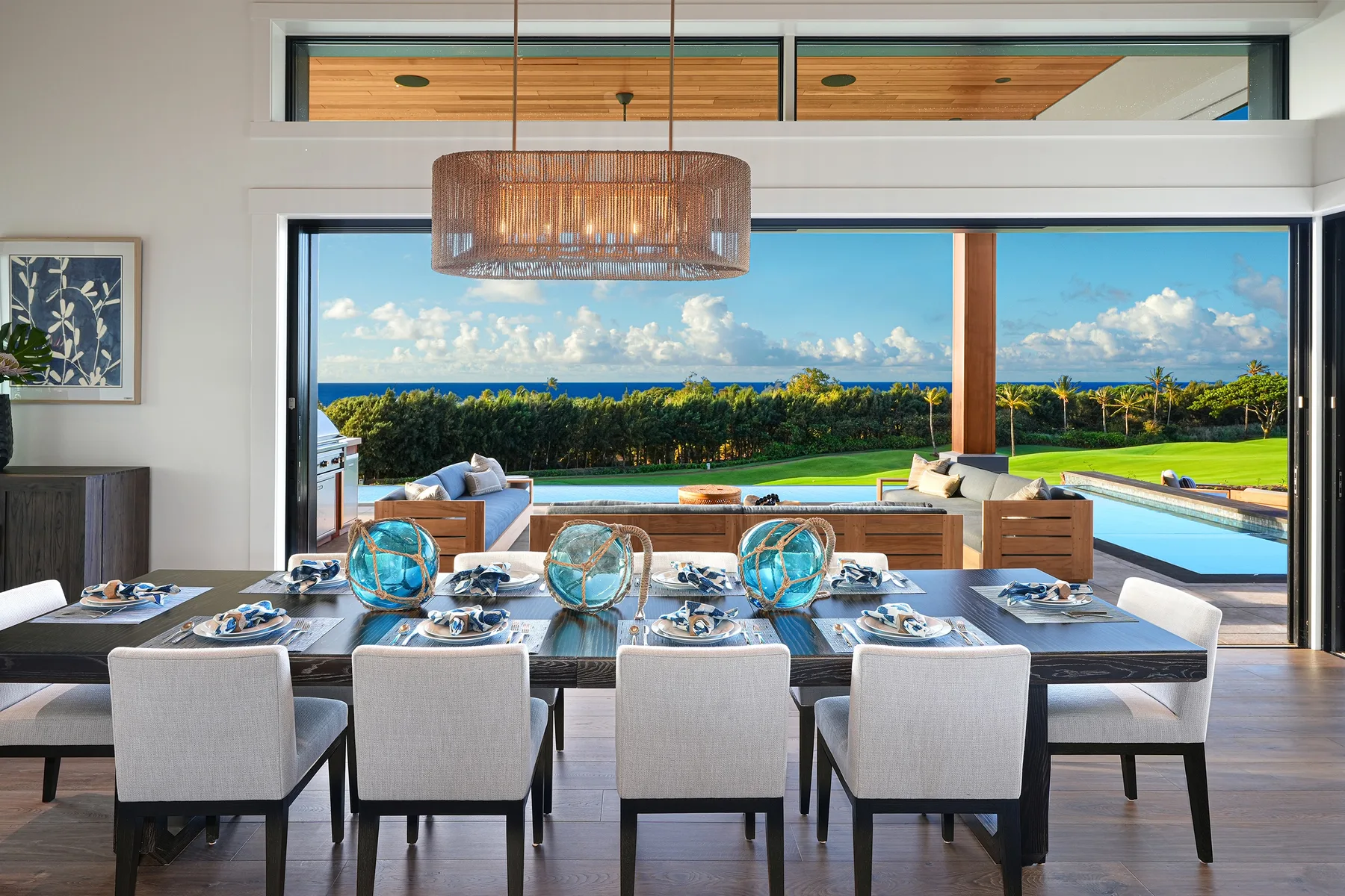A dining area opens onto a patio with a swimming pool and ocean view.