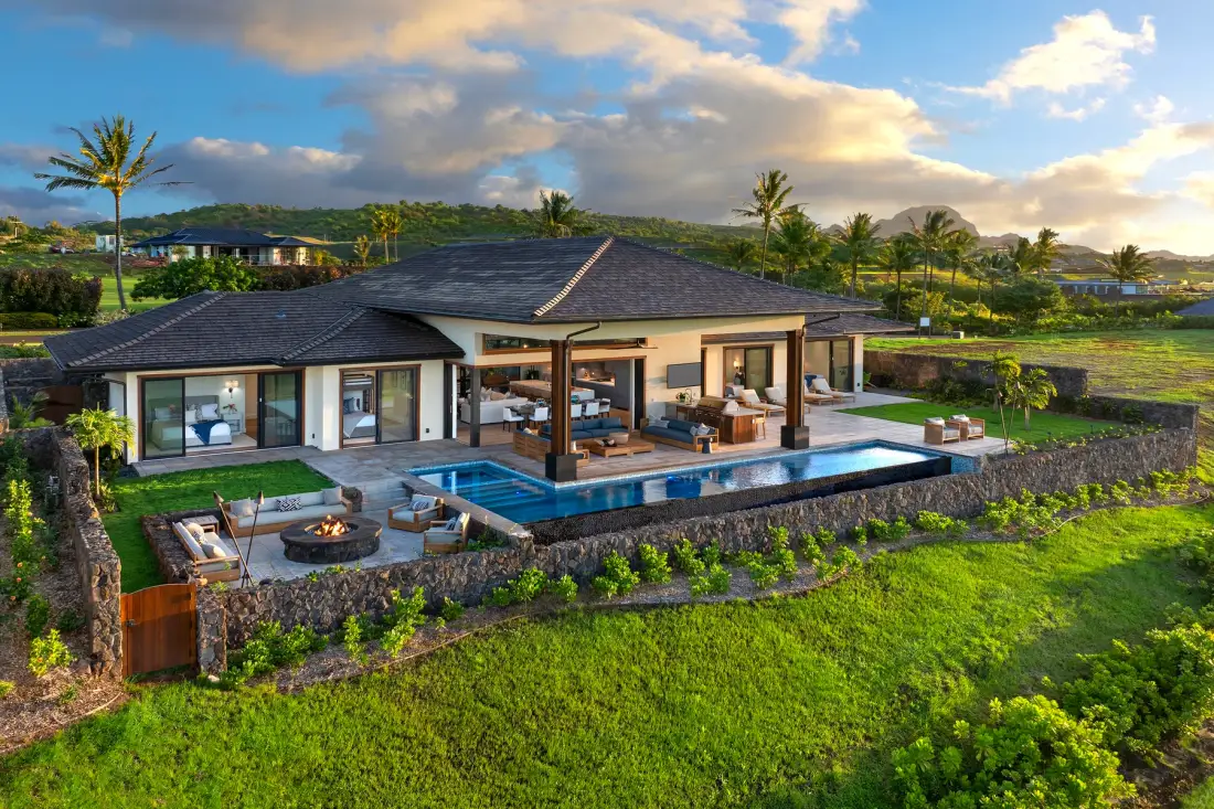 A modern house opens onto a patio with a swimming pool and landscaped grounds.