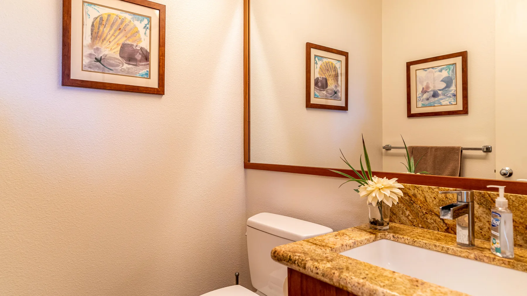 A bathroom vanity with a sink, mirror, and framed artwork.