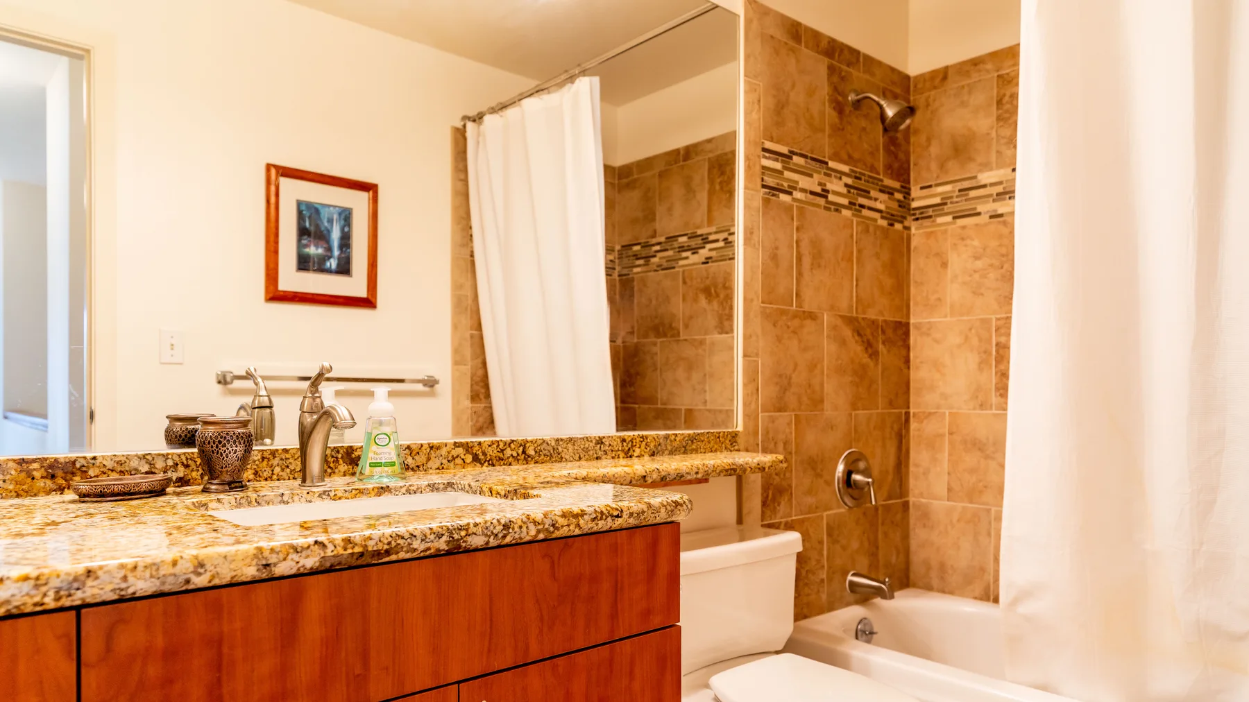 A bathroom with a vanity, sink, and a bathtub behind a shower curtain.