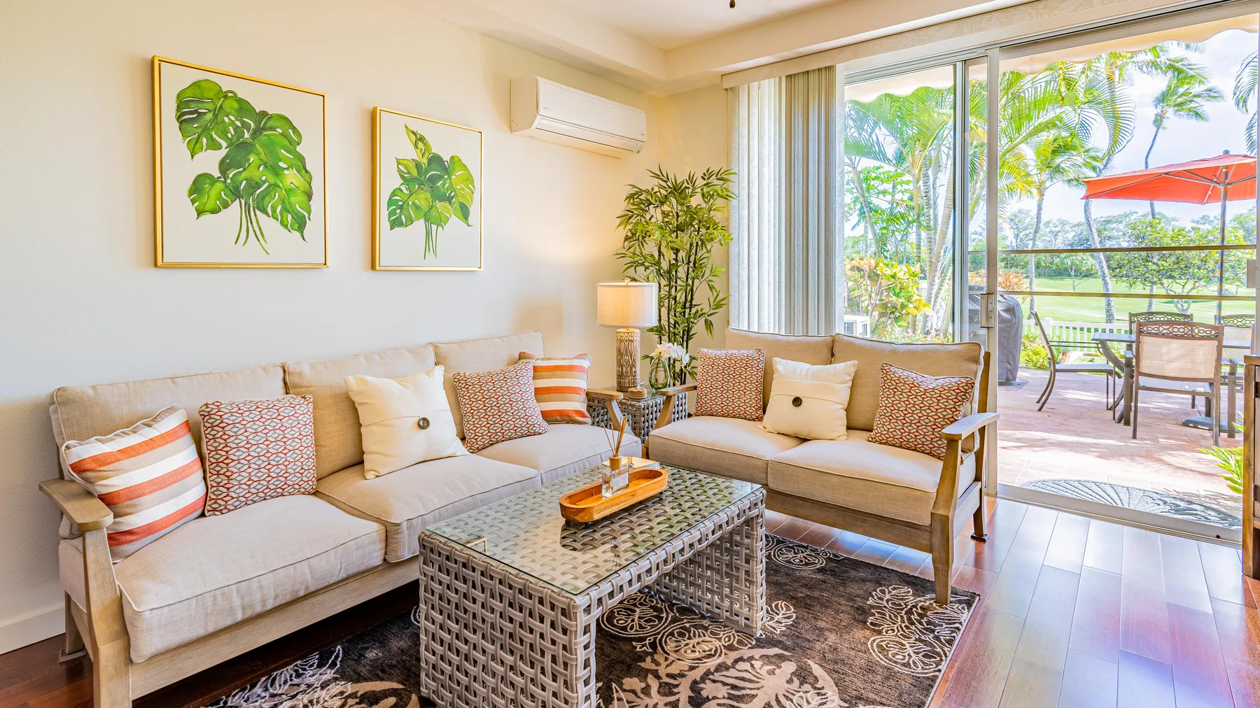 A bright living room with cushioned seating and glass doors opening to a patio.