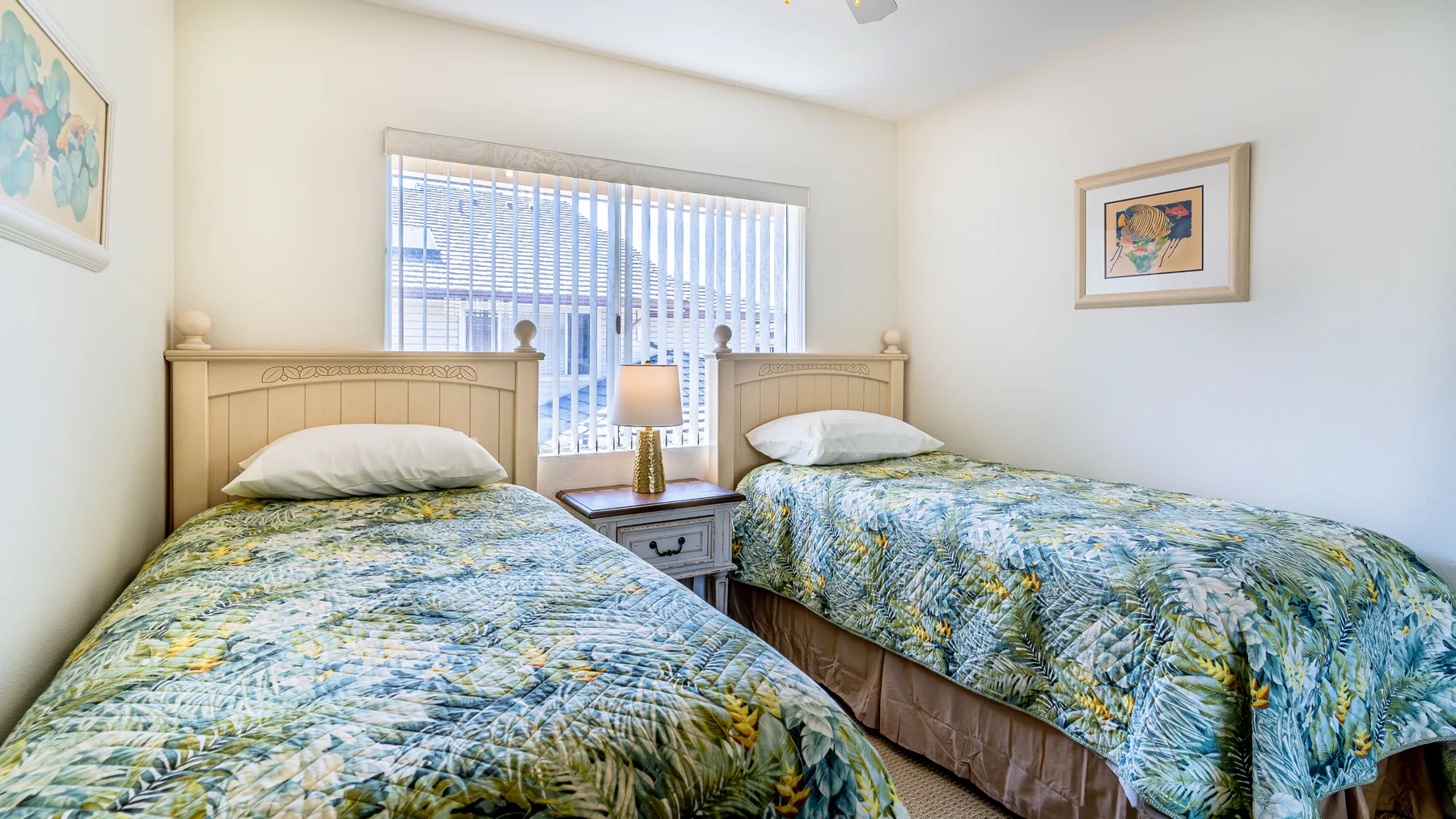 A bedroom with two beds covered in blue and green patterned bedding.