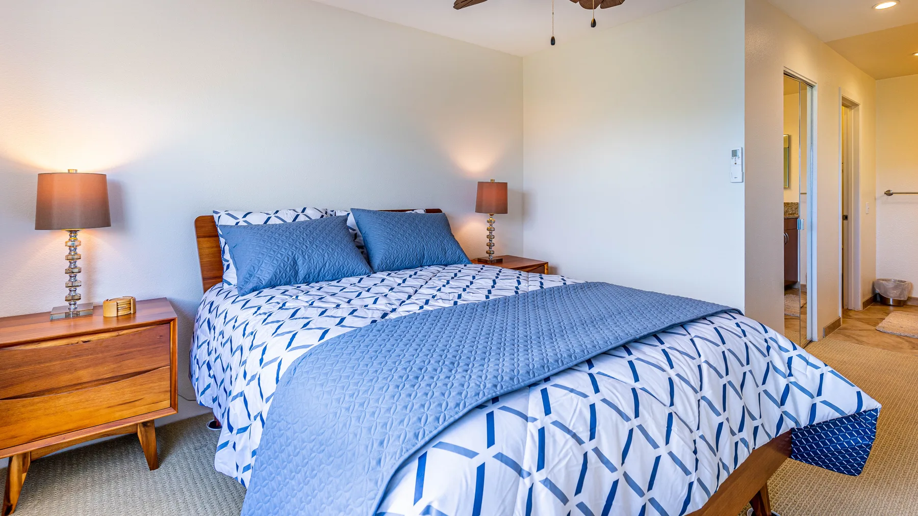 A bedroom with a bed dressed in blue-and-white patterned bedding.