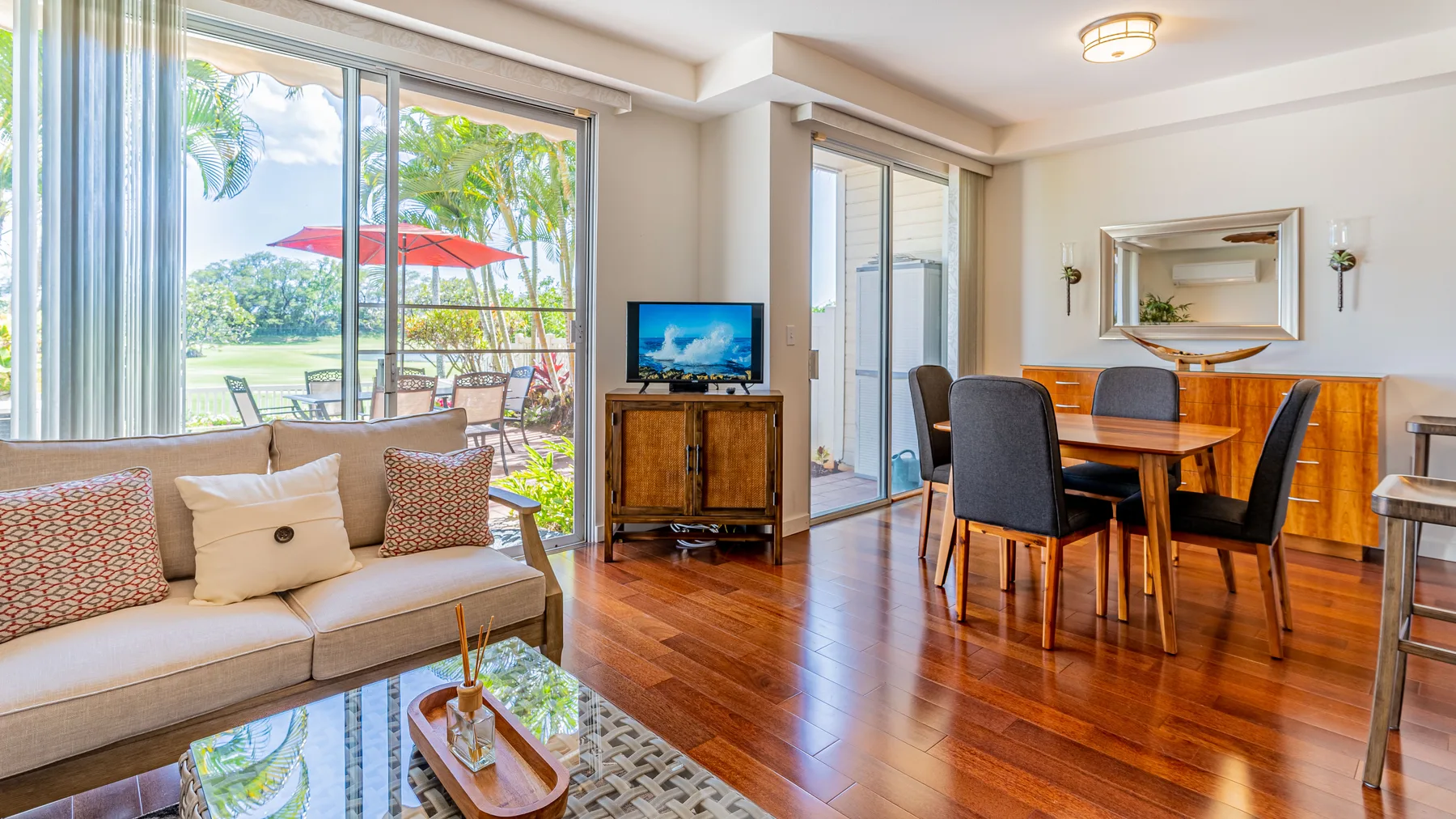 A bright living and dining area with seating, a dining table, and large windows.