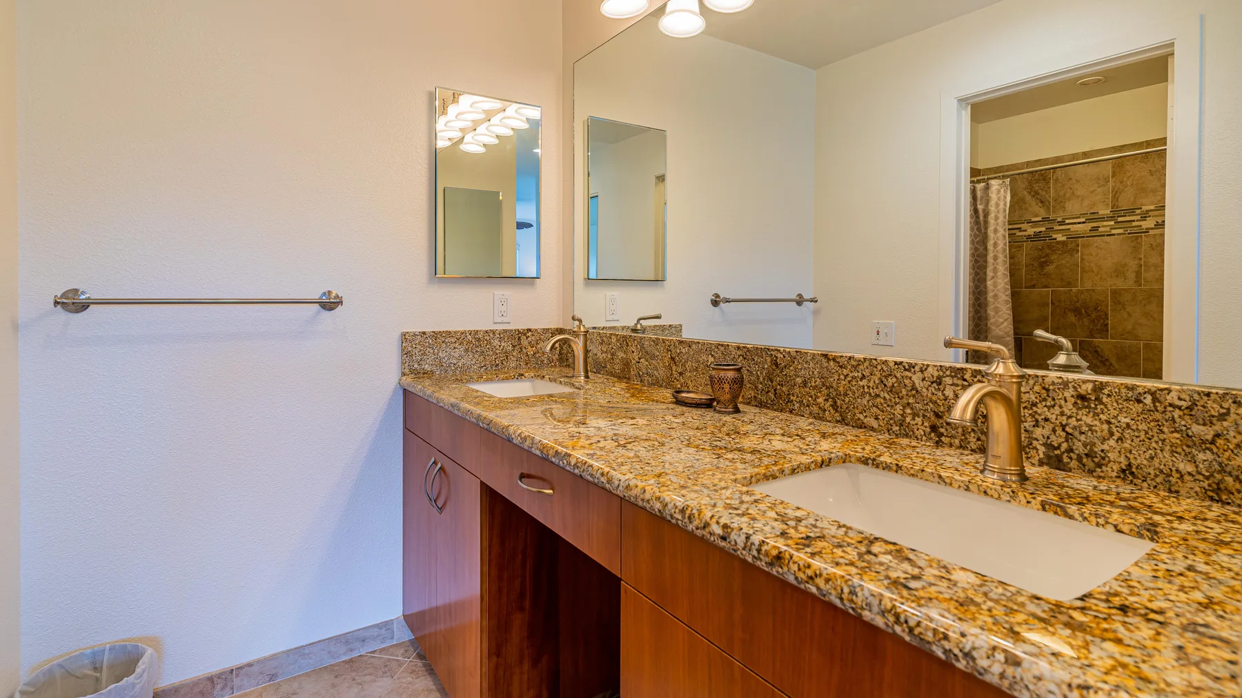 A bathroom vanity with a long countertop, sinks, and wall mirrors.