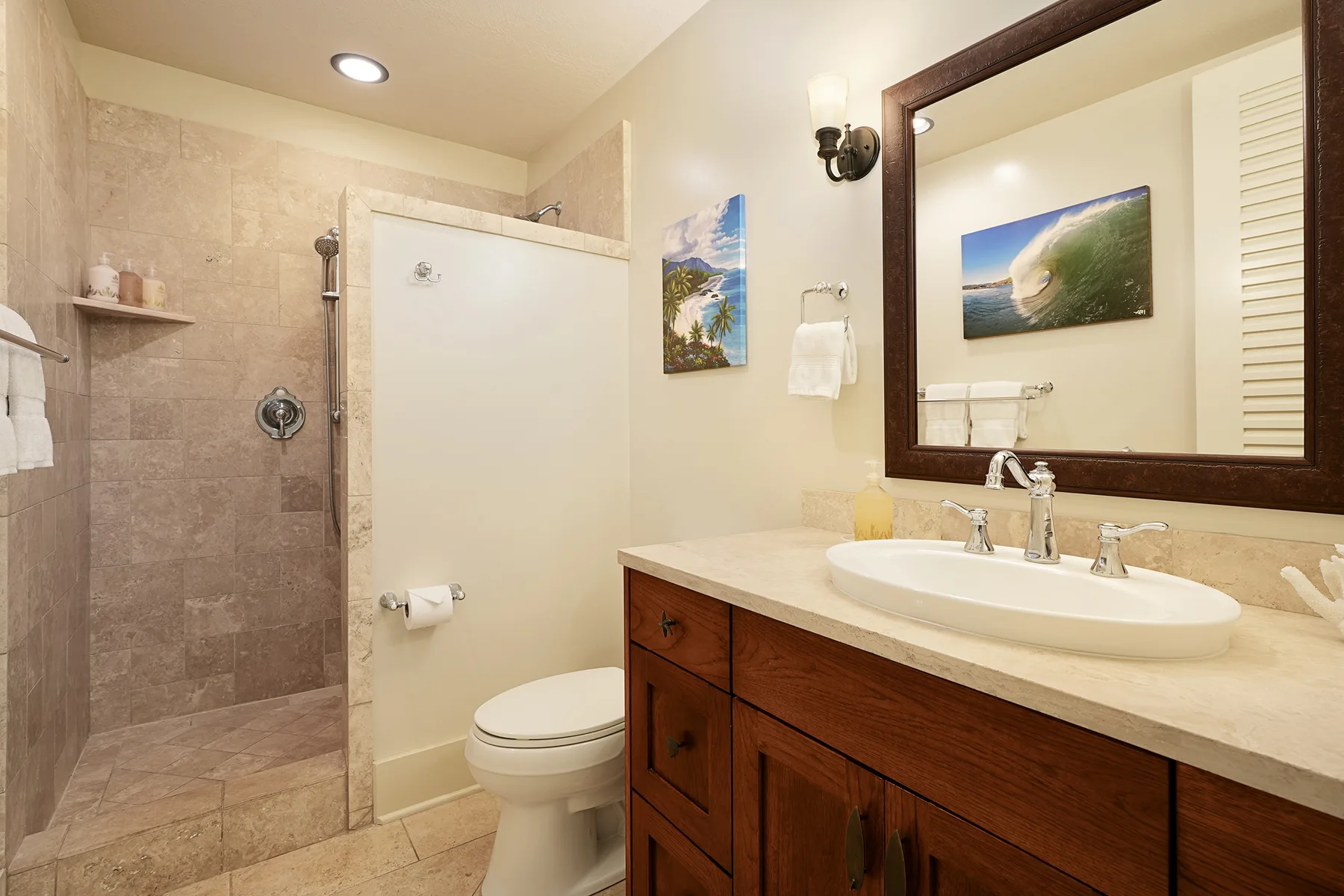 Un baño con ducha de azulejos, inodoro y tocador con un espejo grande.
