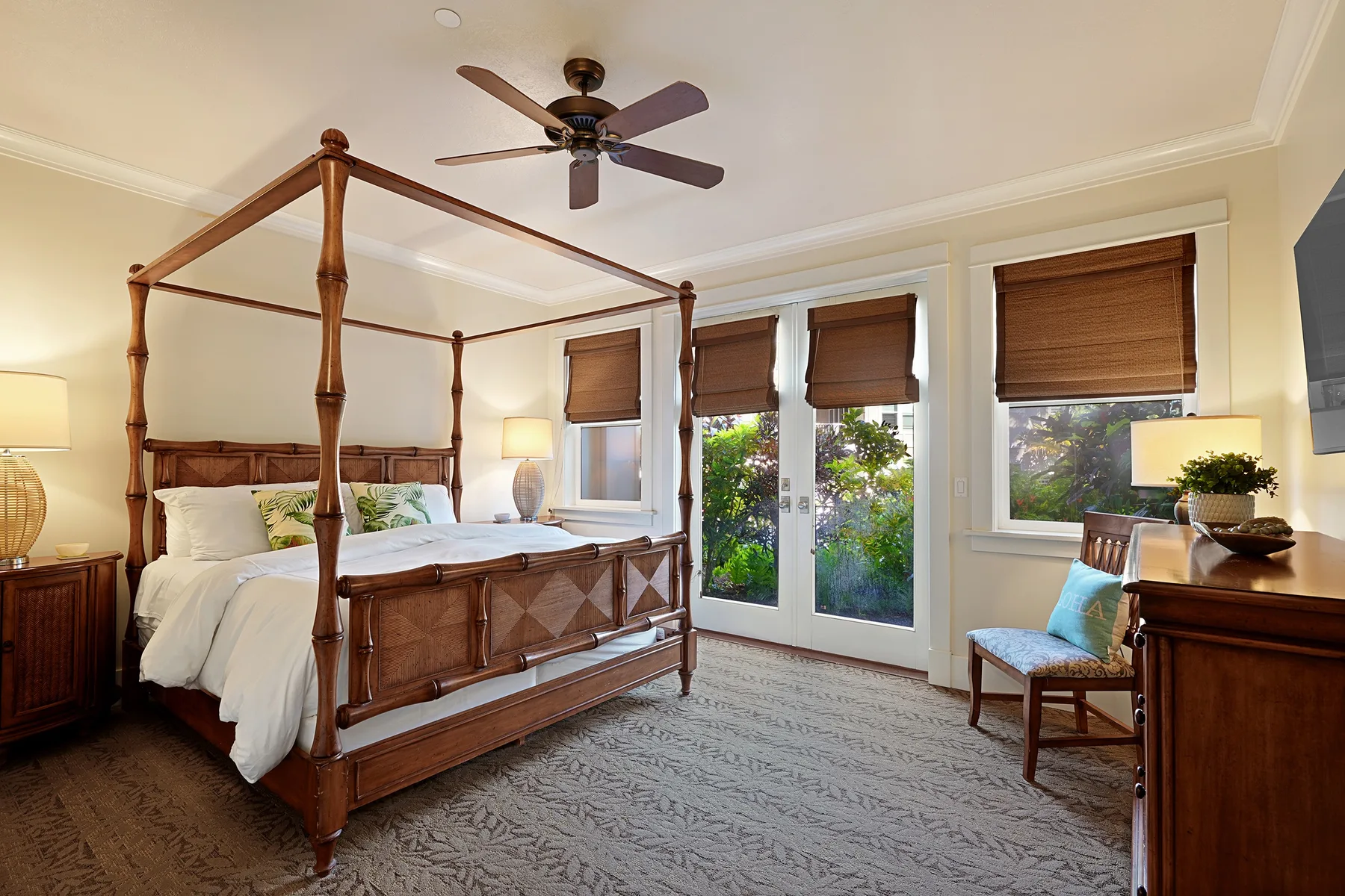 Un dormitorio con una cama con dosel de madera y ventanas con vistas a la vegetación.