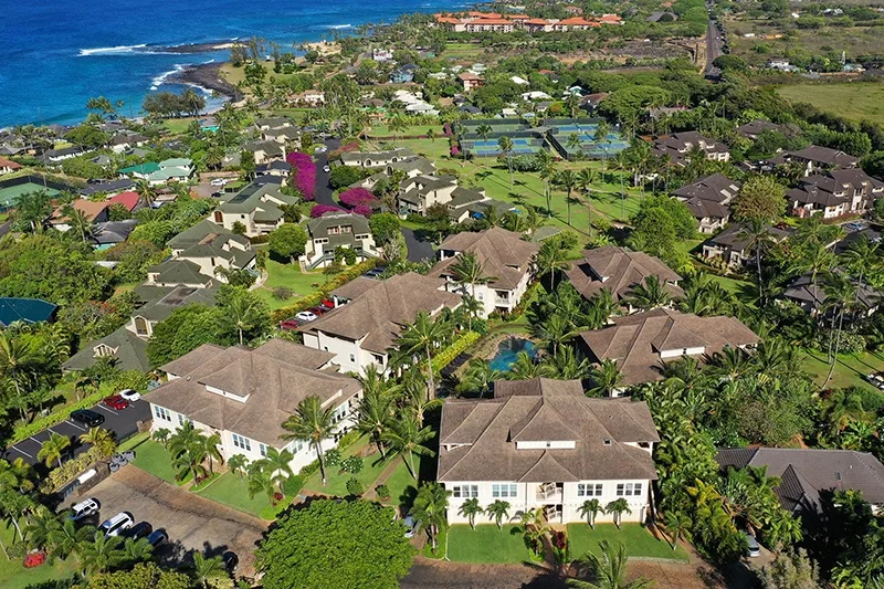Vista aérea de un complejo residencial costero con viviendas y canchas de tenis.