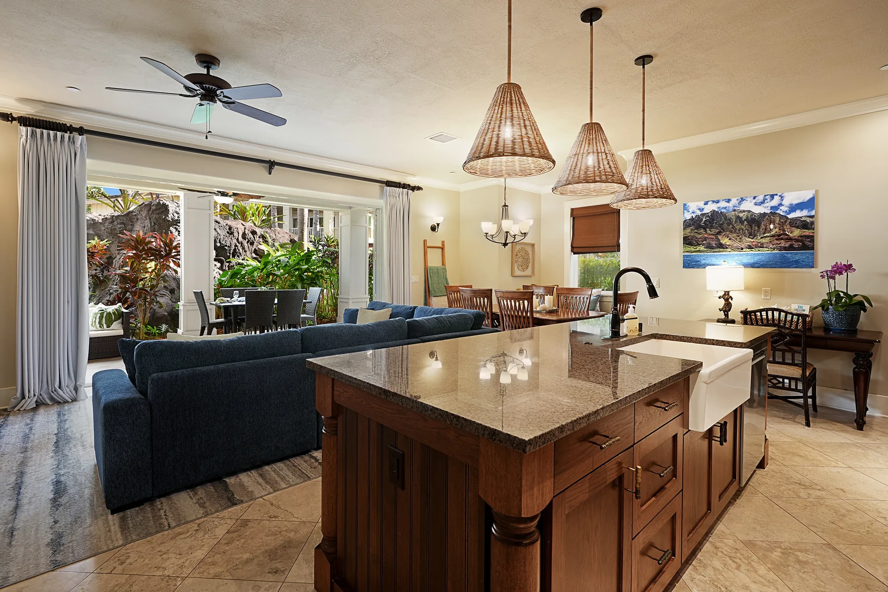 Un espacio abierto de sala y comedor con una isla de cocina y lámparas colgantes.