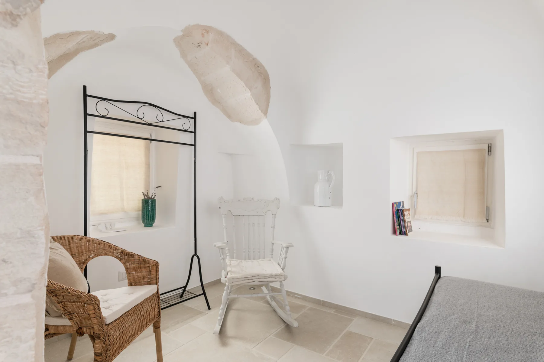 Una luminosa zona de estar con asientos de mimbre, una mecedora y una ventana empotrada.