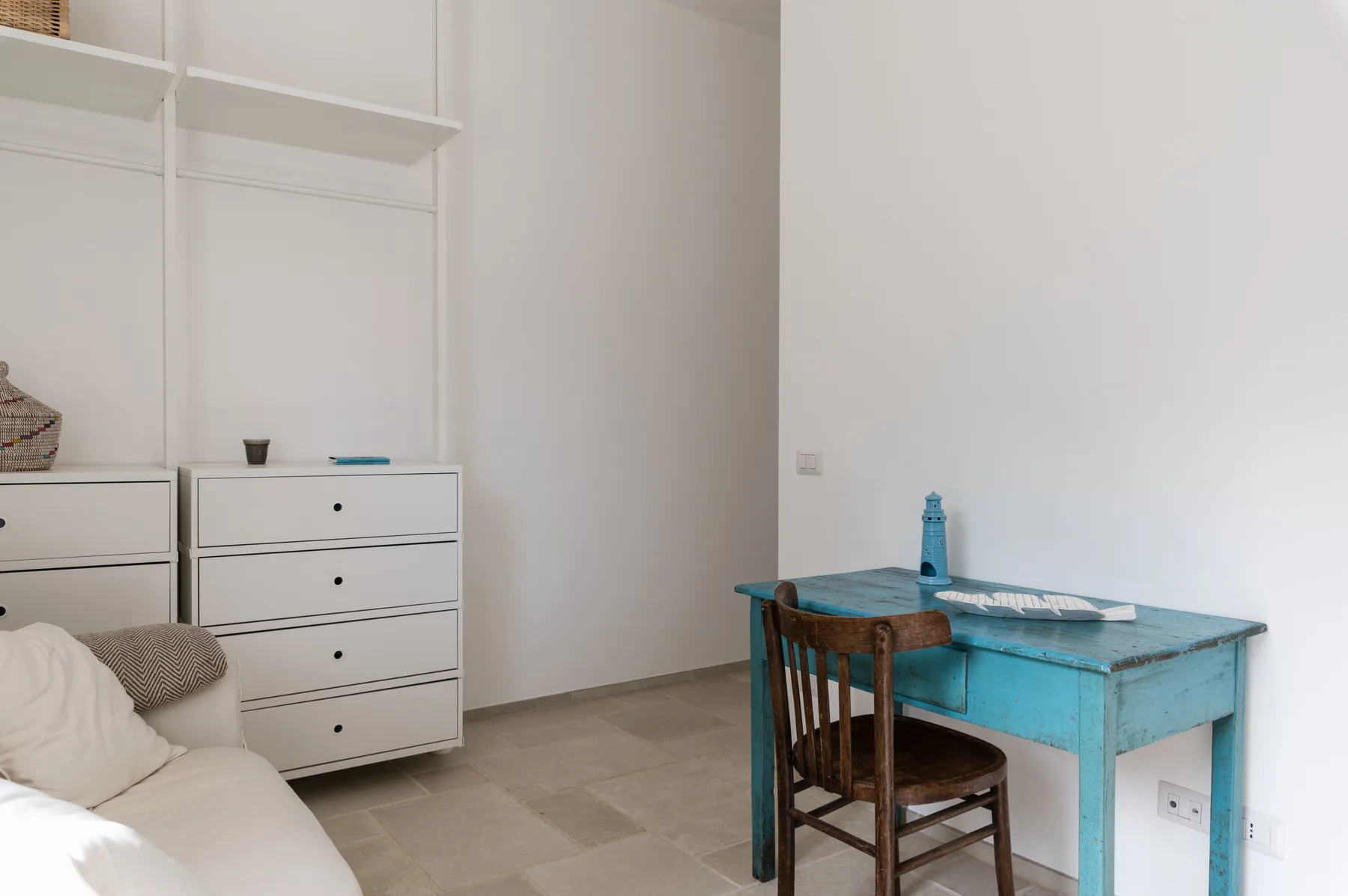 Un dormitorio luminoso con una cama y un escritorio turquesa junto a una silla.
