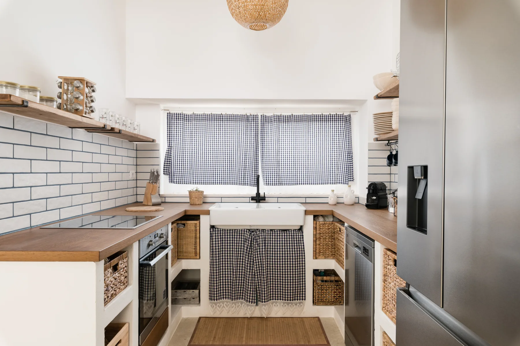 Una cocina luminosa con encimeras de madera, paredes de azulejos y un fregadero central.