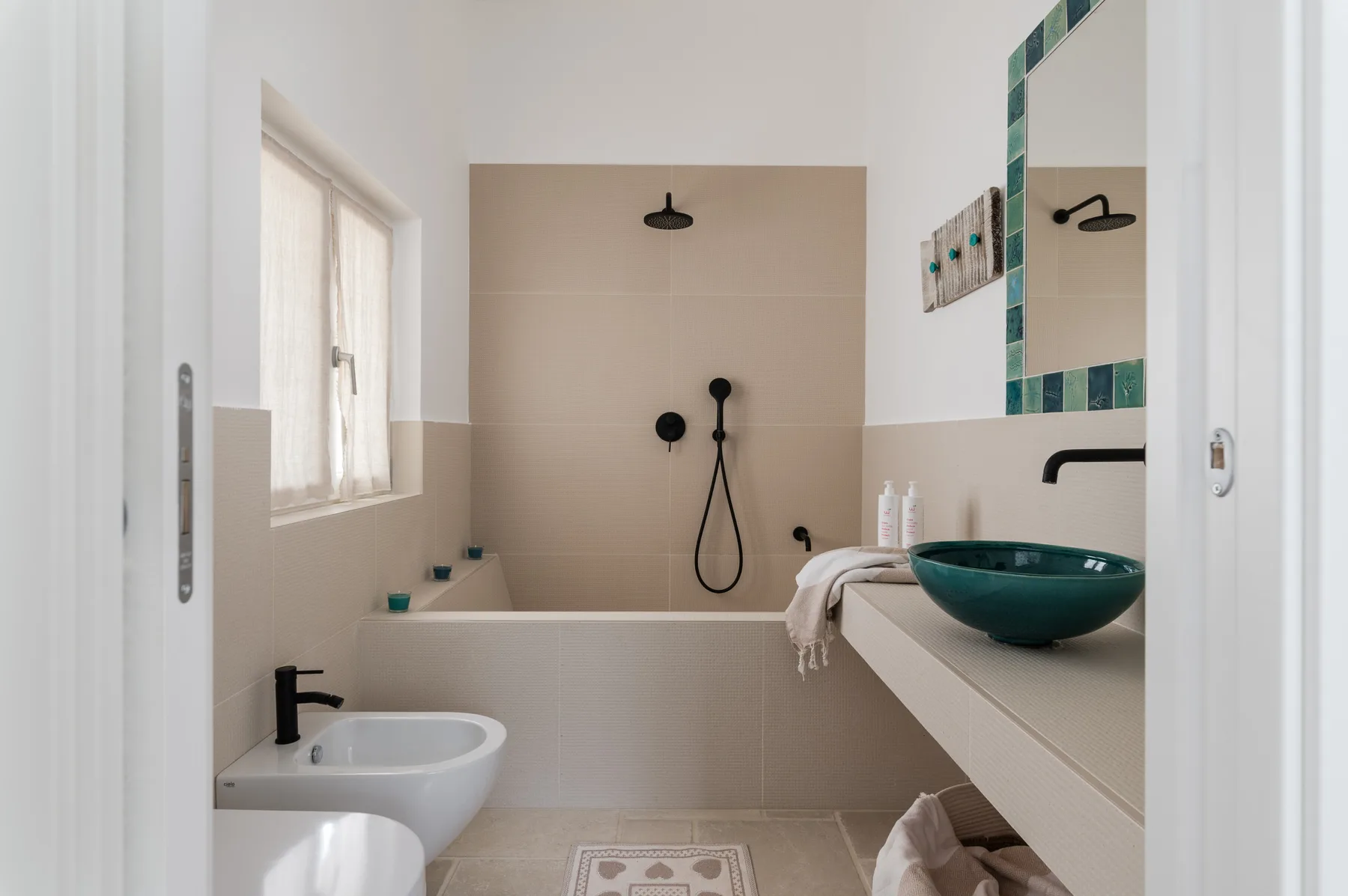Un baño luminoso con ducha a ras de suelo y un lavabo verde azulado.