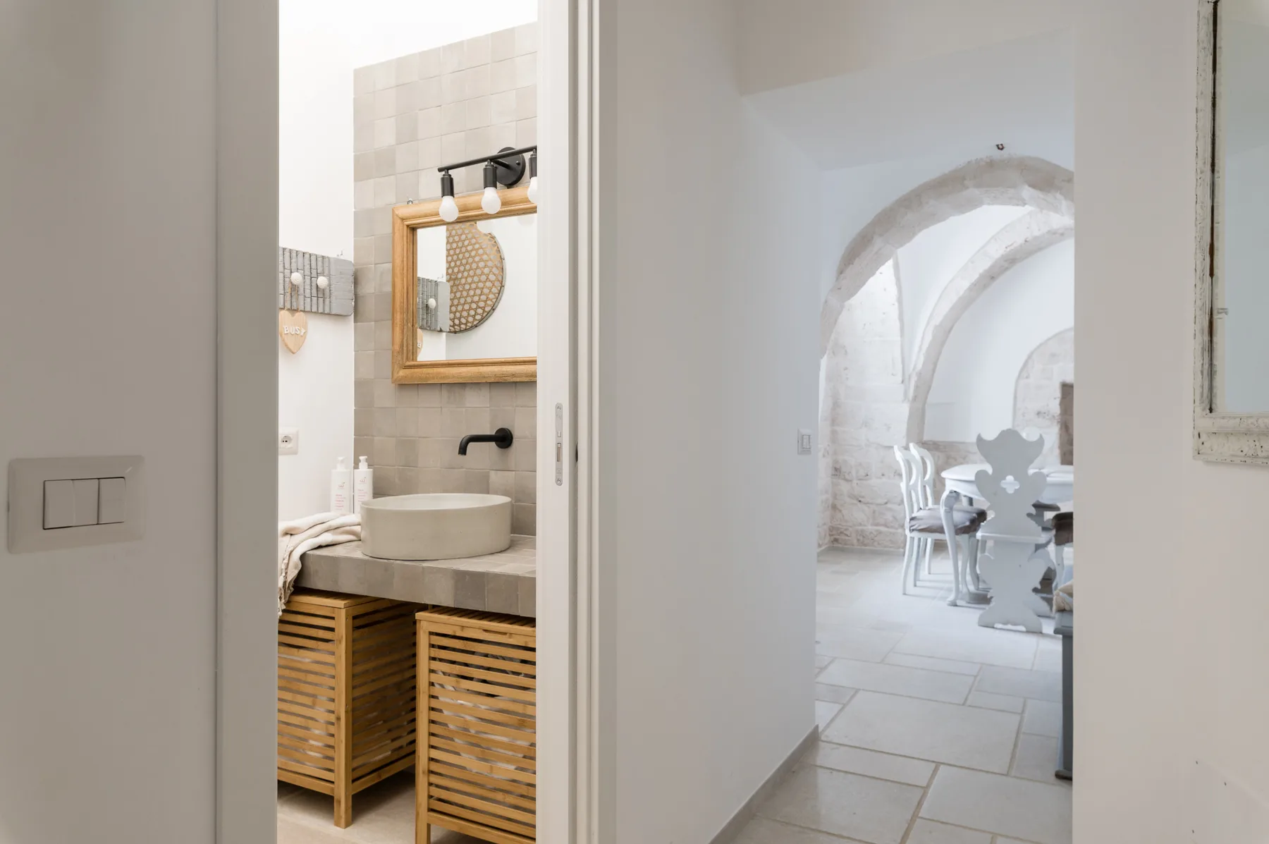 Un lavabo de baño da a un comedor luminoso a través de un arco.