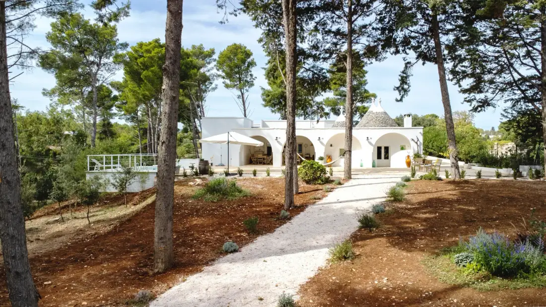 Un edificio blanco se encuentra entre árboles al final de un sendero curvo.