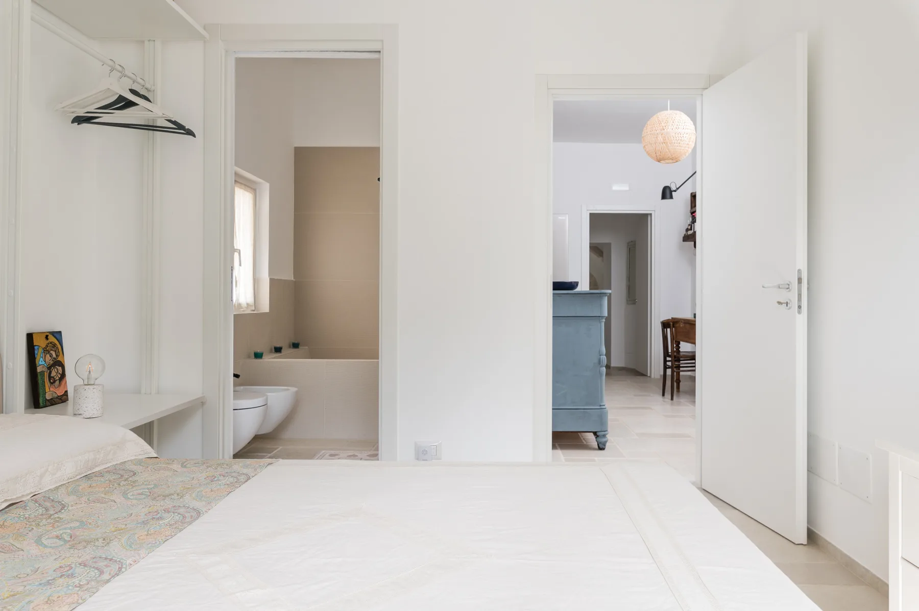 Un dormitorio con un armario abierto y vistas al baño y la sala contiguos.
