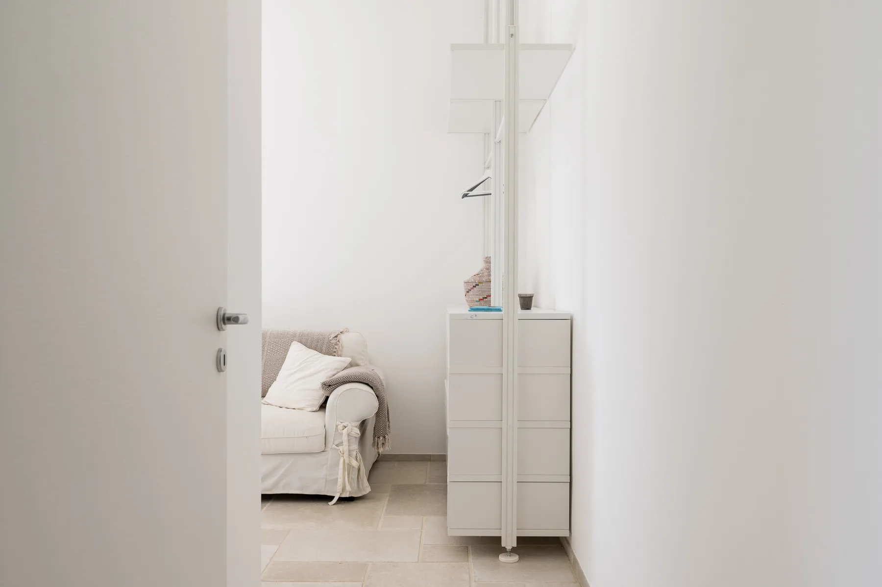 Un dormitorio luminoso con una cama y una cómoda alta al lado.