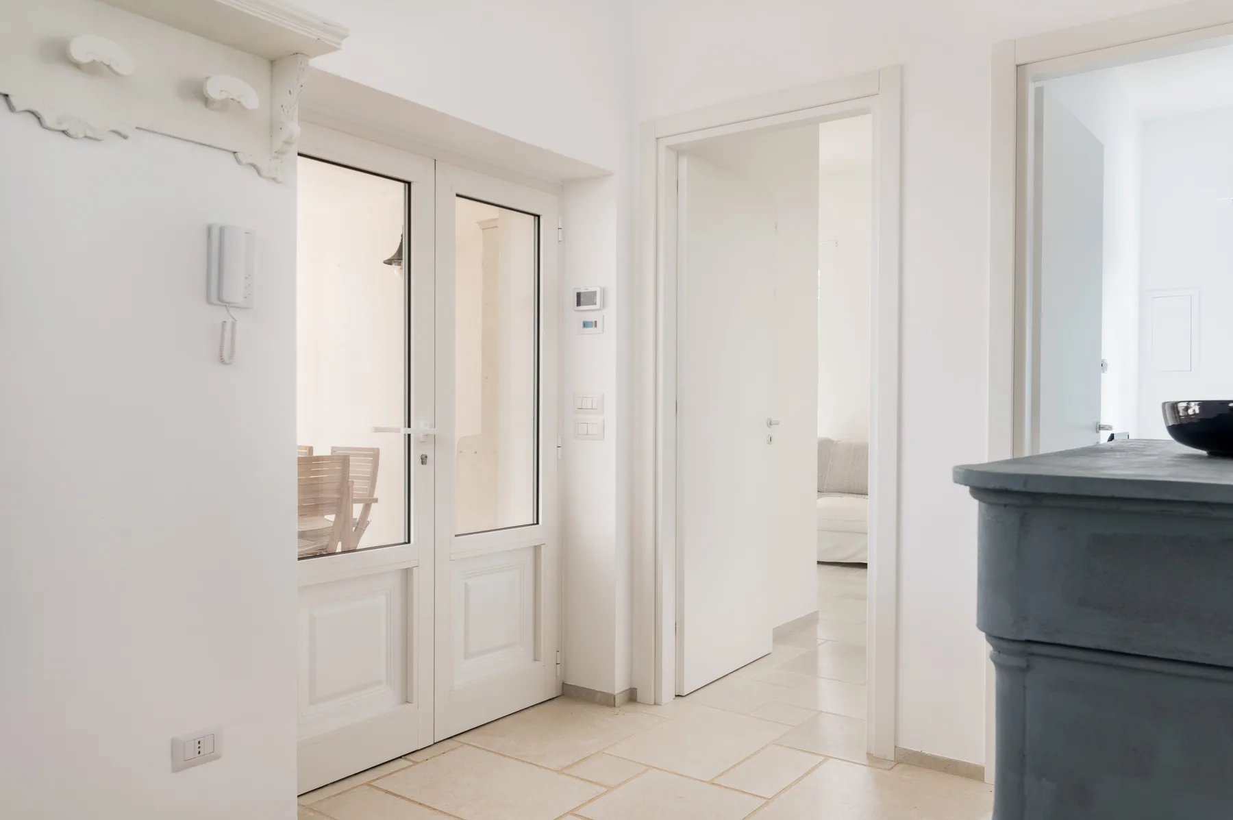 Una entrada blanca y luminosa da a una habitación con una cama.