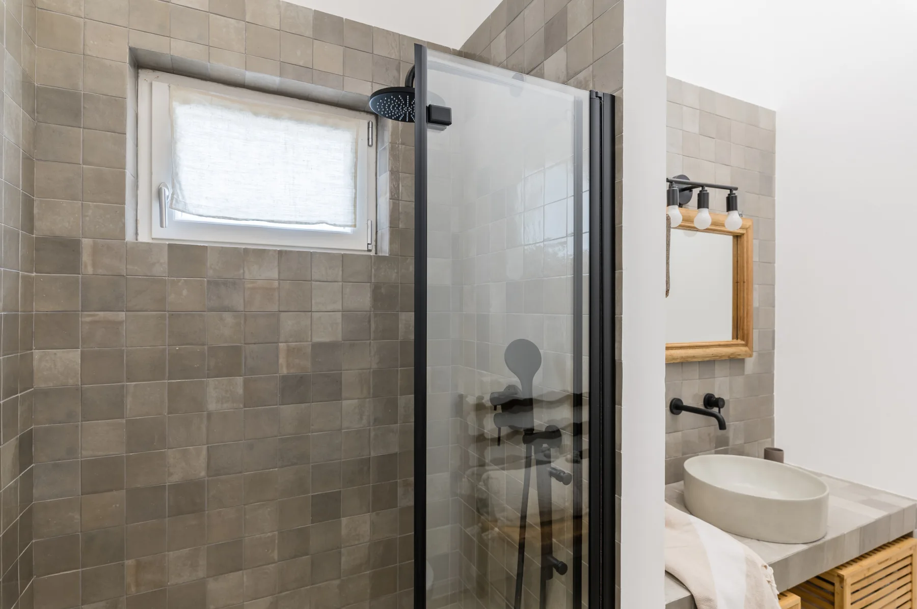 Un baño alicatado con una ducha de vidrio y un lavabo.