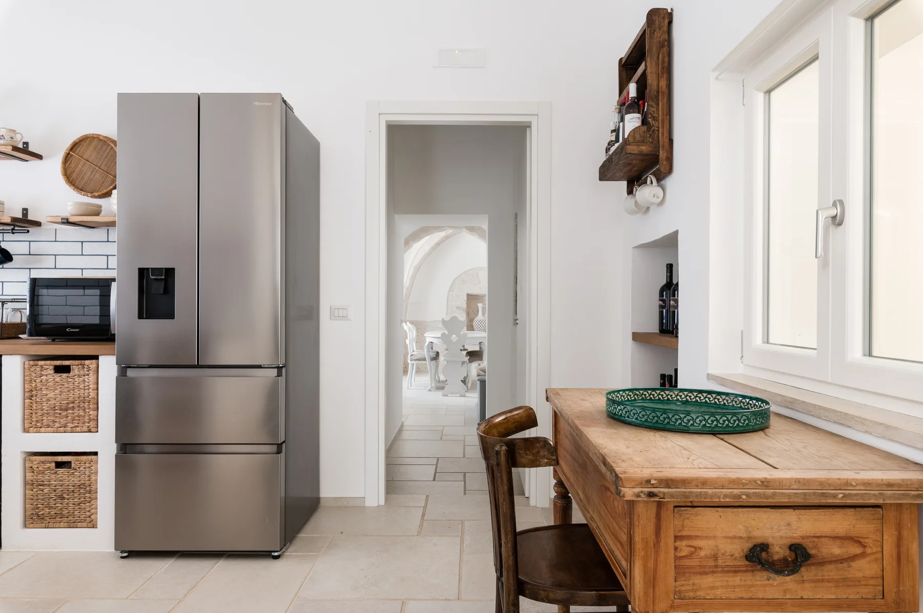 Una cocina luminosa con un refrigerador de acero inoxidable y una mesa de madera junto a la ventana.