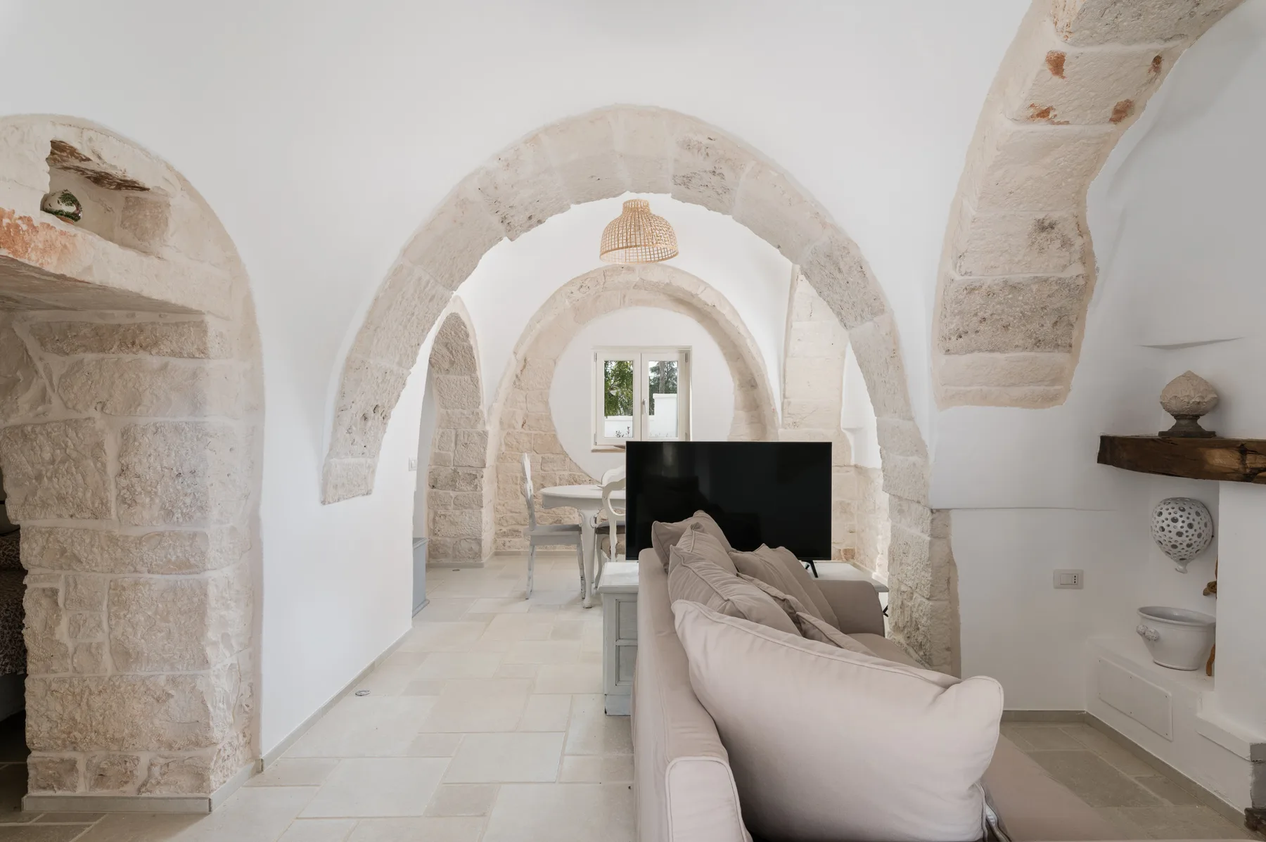 Una sala luminosa con asientos claros bajo una serie de arcos de piedra.